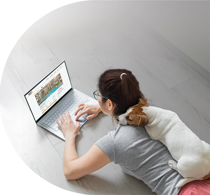 Woman lounging using laptop computer with small dog laying on her back